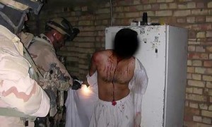 A prisoner in Iraq, held at gunpoint by US soldiers. Credit: AP